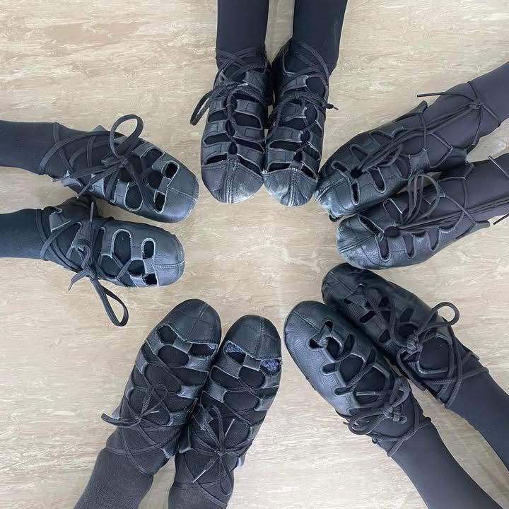 Irish dance shoes arranged in a circle on a wood floor